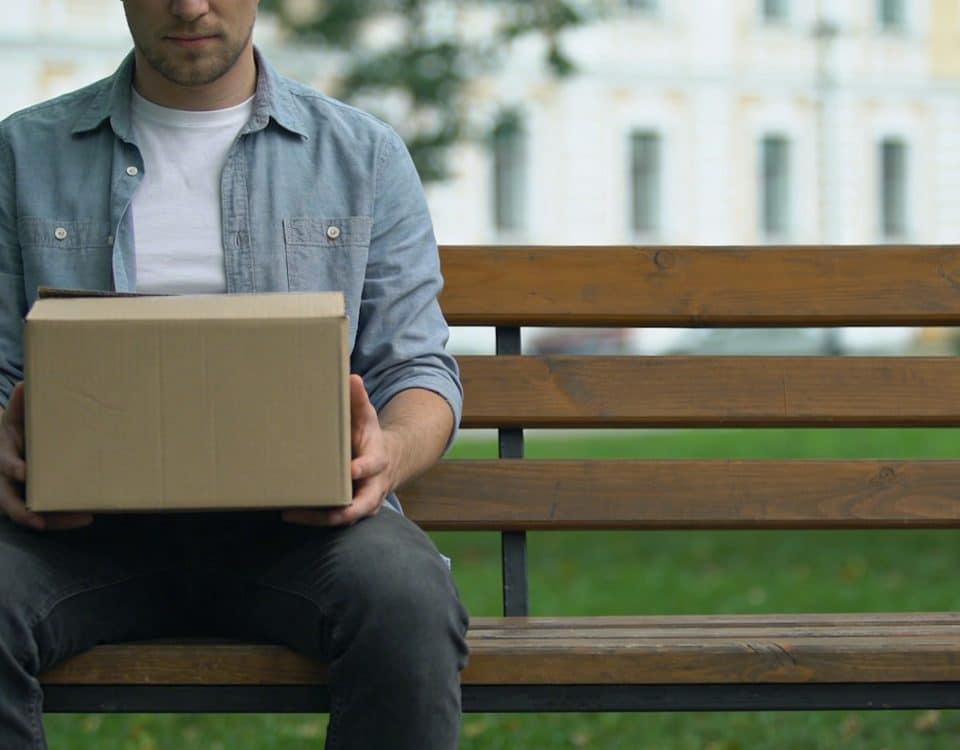 homme assis seul sur un banc avec carton