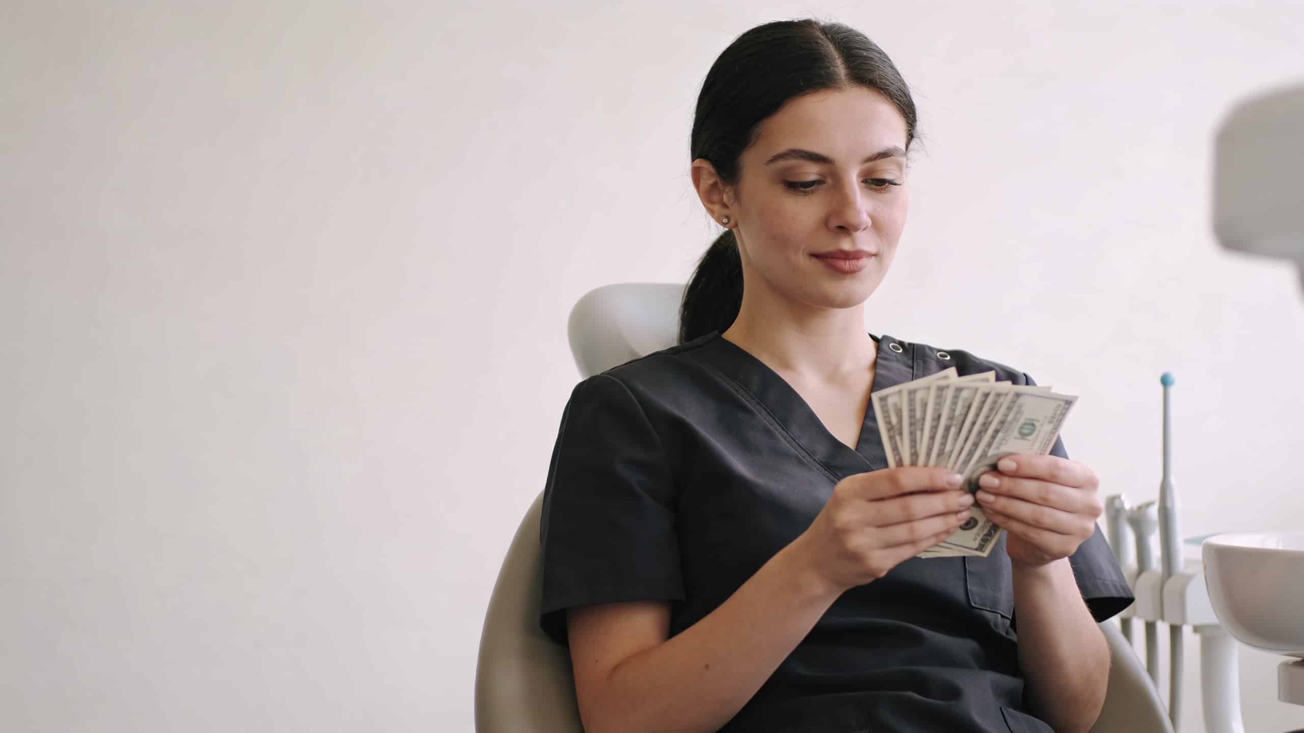 Assistante dentaire assise comptant des billets