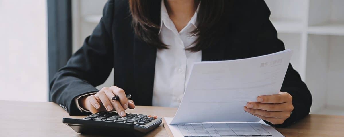jeune agent immobilier assis au bureau calculatrice et fiches de paie