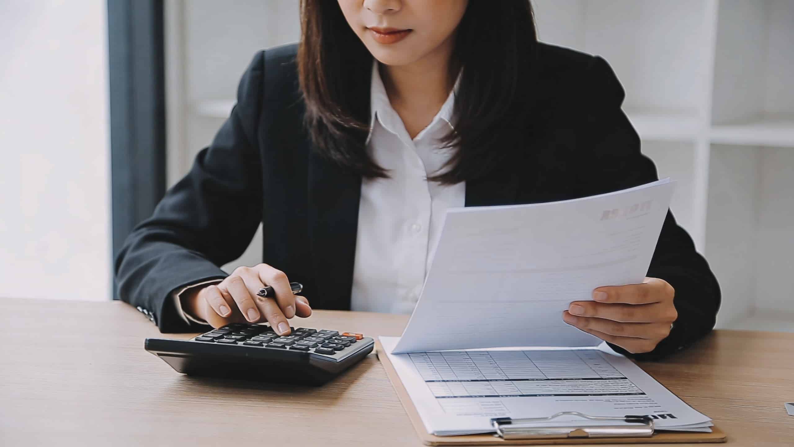 jeune agent immobilier assis au bureau calculatrice et fiches de paie