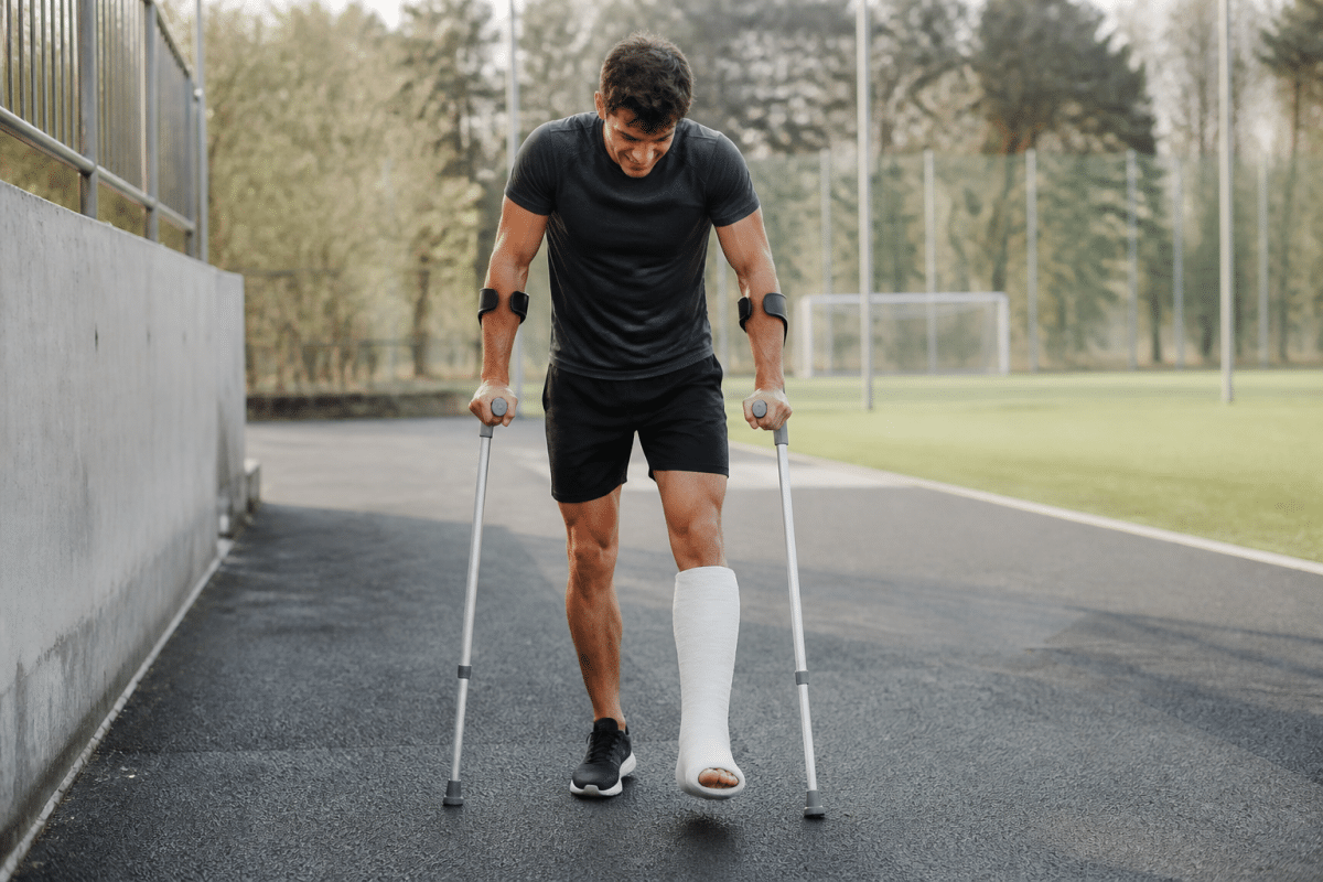 Athlete with cast limping painfully during rehabilitation exercise.