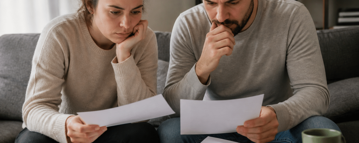 Couple assis examinant ensemble des documents financiers importants.