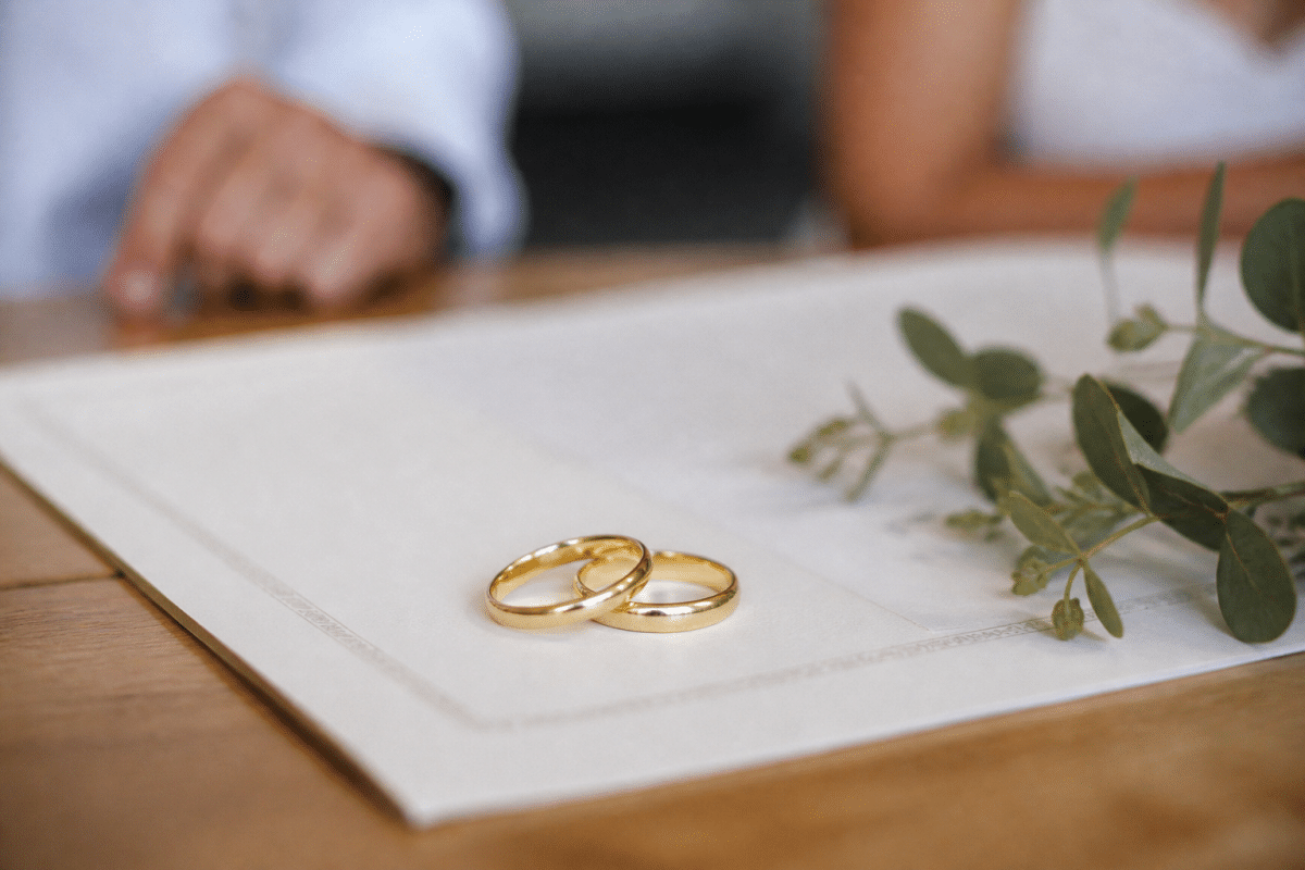 Deux alliances dorées posees sur document legal de mariage