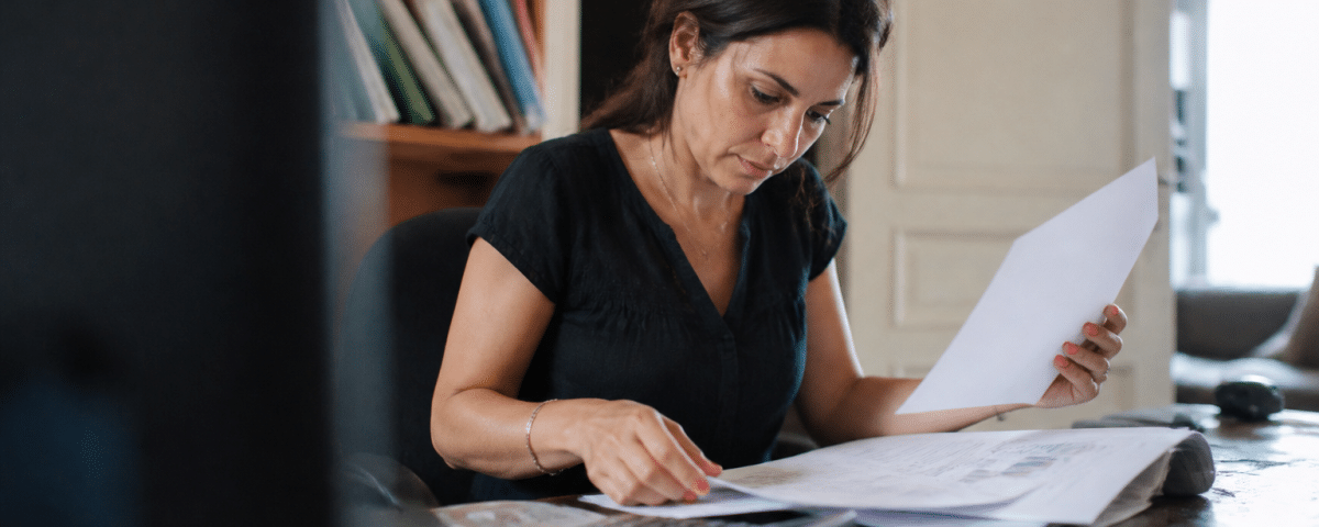 Femme assise a son bureau consultant documents financiers.