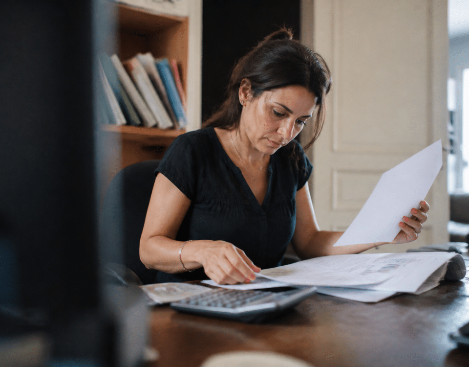 Femme assise a son bureau consultant documents financiers.