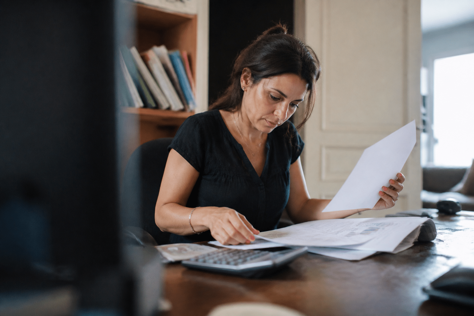 Femme assise a son bureau consultant documents financiers.