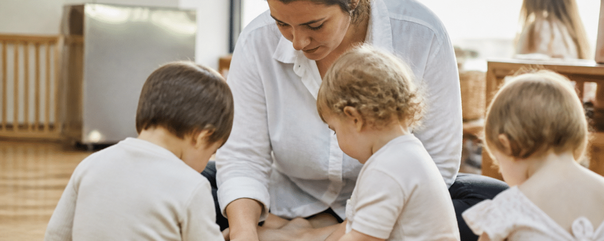 Femme s'occupant d'enfants en bas age assis.