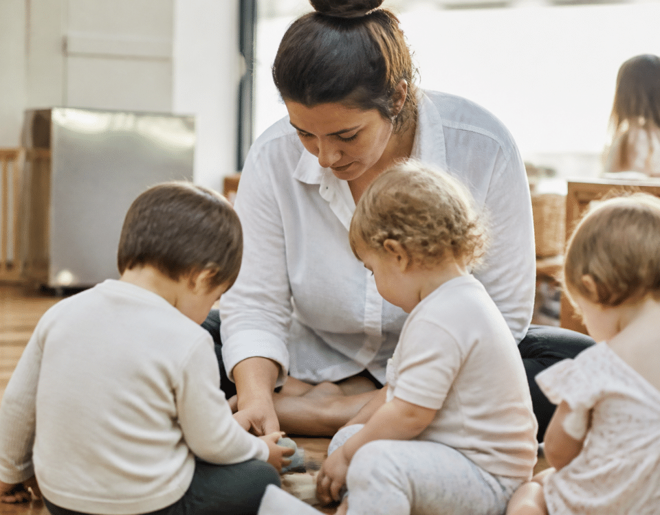 Femme s'occupant d'enfants en bas age assis.