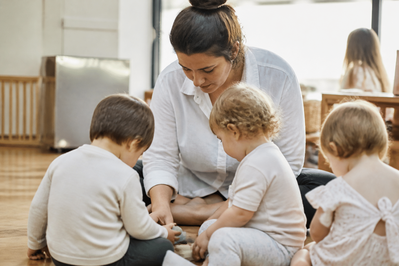 Femme s'occupant d'enfants en bas age assis.