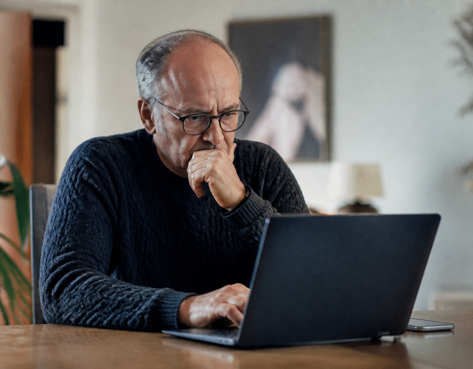 Homme age assis devant ordinateur consultant offres emploi.