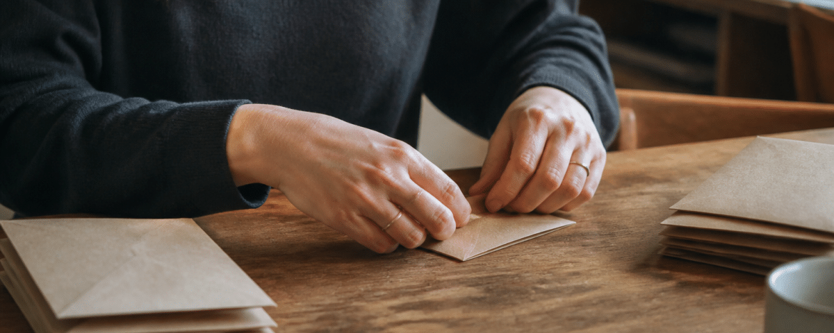 Mains pliant enveloppes brunes sur table domestique.