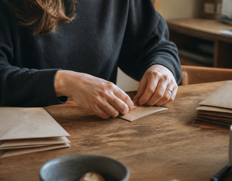 Mains pliant enveloppes brunes sur table domestique.