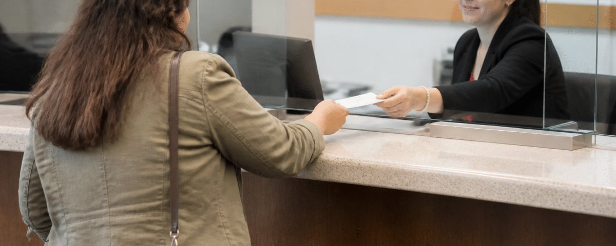 Personne tenant un cheque a la banque, comptoir de service visible