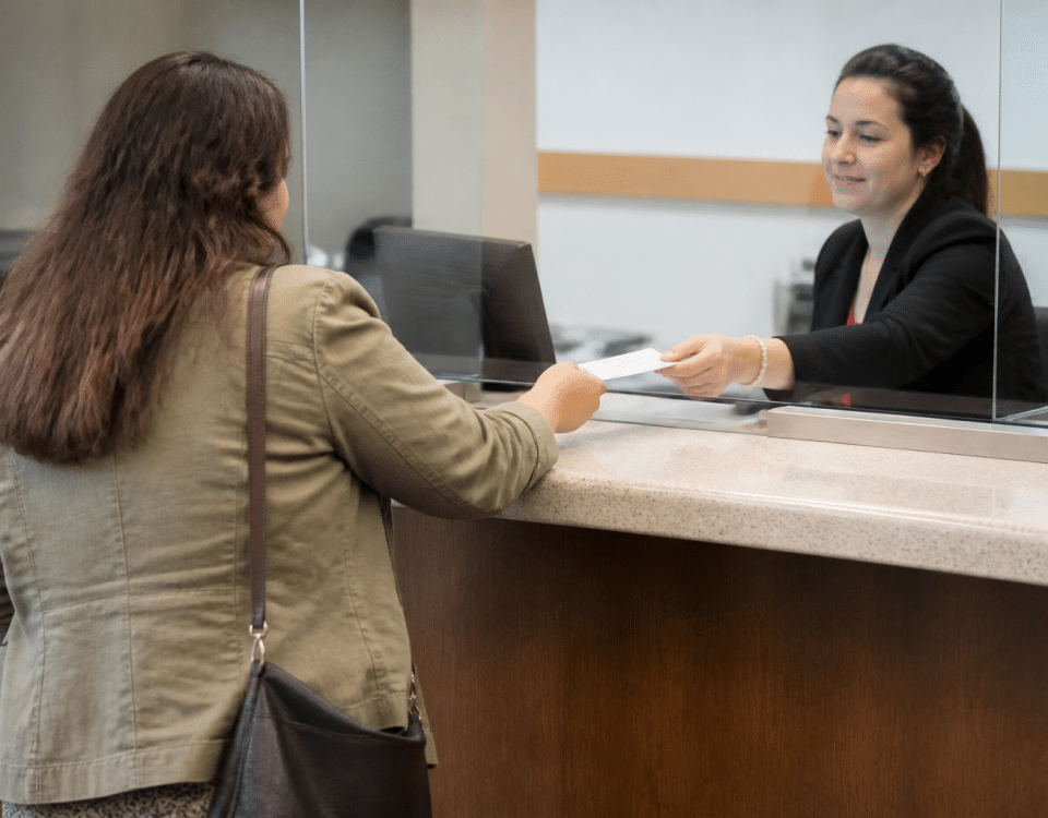 Personne tenant un cheque a la banque, comptoir de service visible