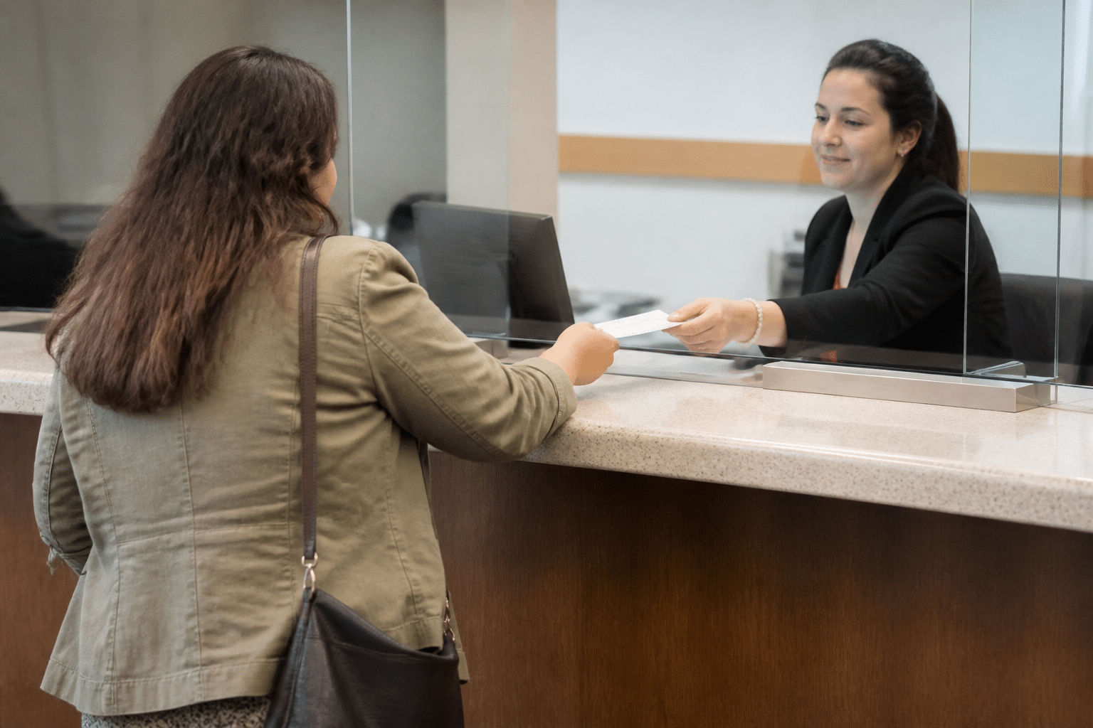 Personne tenant un cheque a la banque, comptoir de service visible