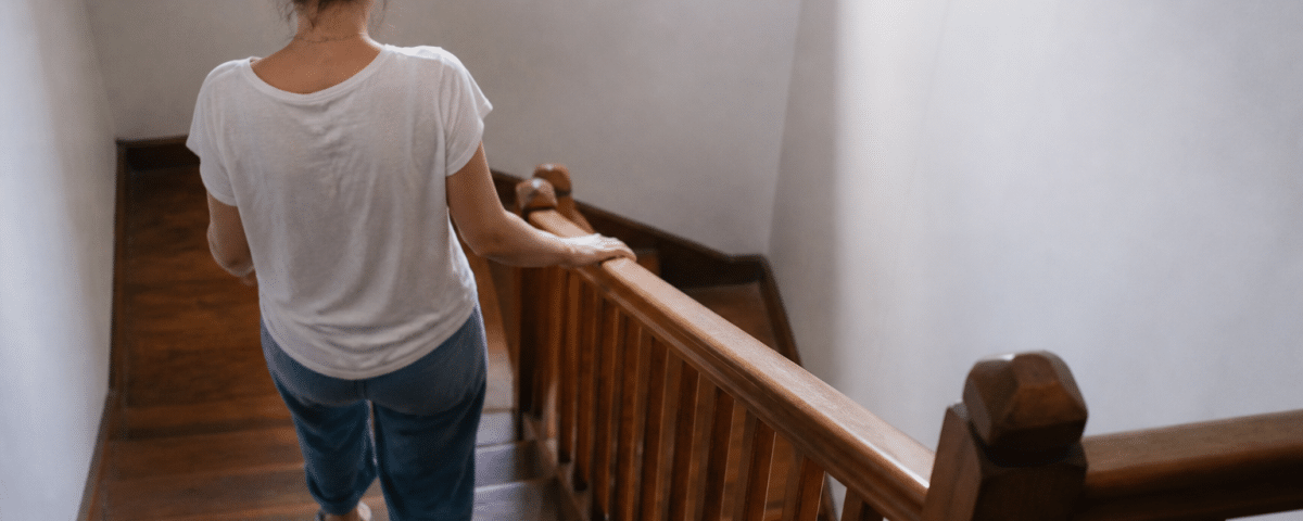 Personne descendant escalier en bois avec rampe