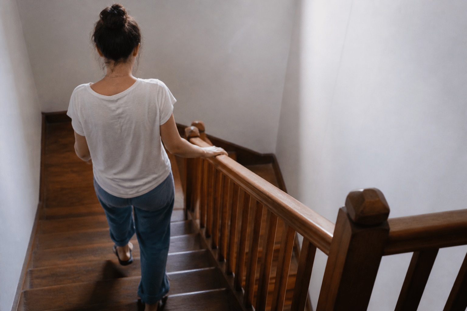 Personne descendant escalier en bois avec rampe