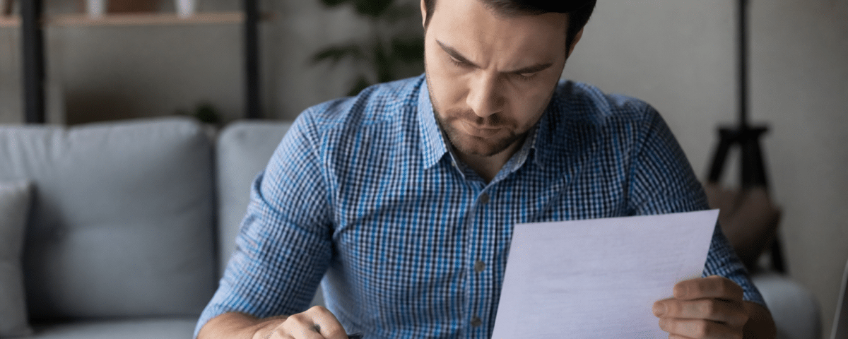 Personne assise examinant documents financiers et calculatrice.