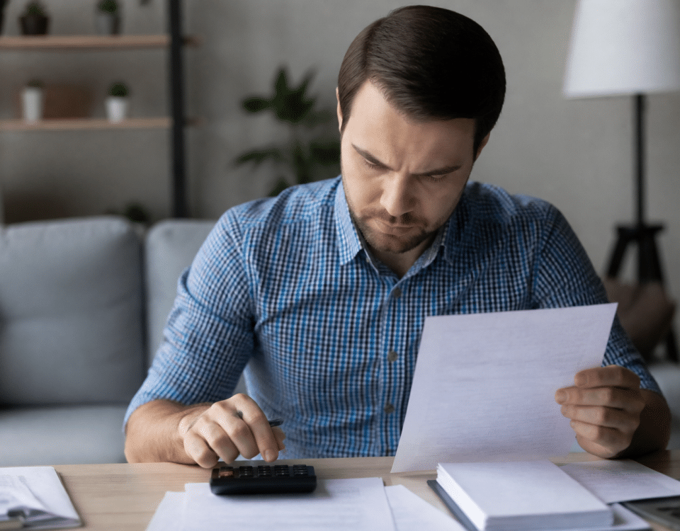 Personne assise examinant documents financiers et calculatrice.