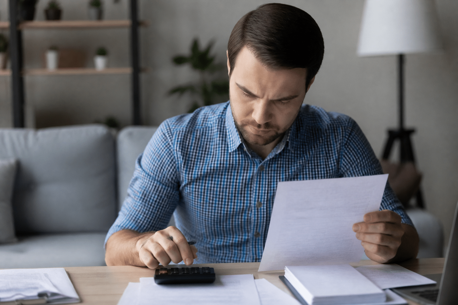 Personne assise examinant documents financiers et calculatrice.