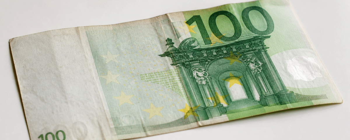 Vieux billet cent euros posé sur surface blanche.