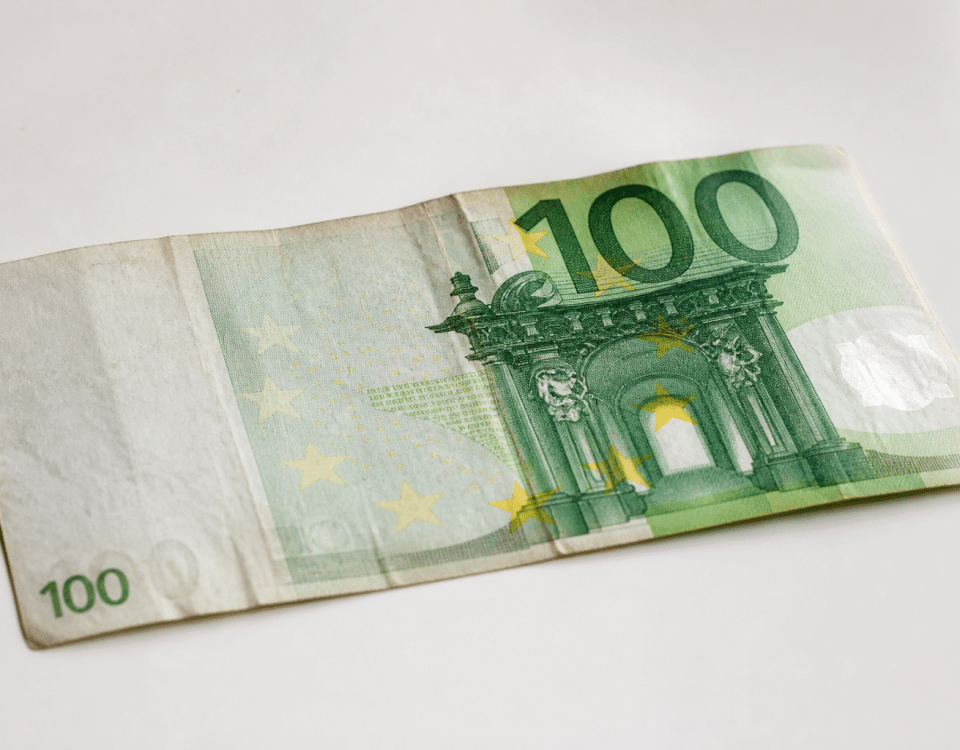 Vieux billet cent euros posé sur surface blanche.